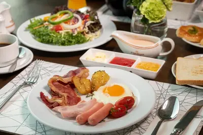 a table with plates of breakfast food on it at Jasmine City Hotel in Bangkok