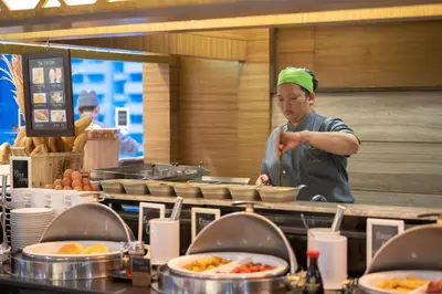 a man in a kitchen preparing food in a kitchen at Jasmine City Hotel in Bangkok