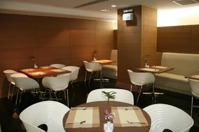 a dining room with tables and white chairs at Baiyoke Suite Hotel in Bangkok