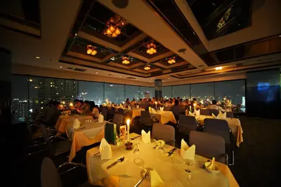 a dining room with white tables and chairs and people at Baiyoke Suite Hotel in Bangkok