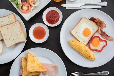 a table with plates of breakfast foods on it at Baiyoke Suite Hotel in Bangkok