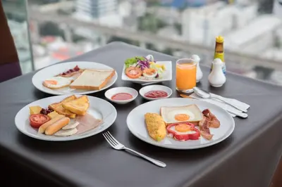 a table with plates of breakfast food on it at Baiyoke Suite Hotel in Bangkok