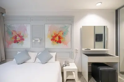 a bedroom with a bed and a desk and a mirror at Pratunam City Inn in Bangkok