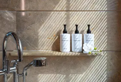 three bottles of wine sitting on a shelf next to a sink at Conrad Bangkok in Bangkok