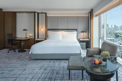 a hotel room with a bed and a table at Conrad Bangkok in Bangkok