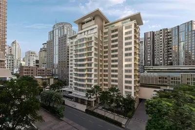 a large apartment building in a city with palm trees at Courtyard by Marriott Bangkok in Bangkok