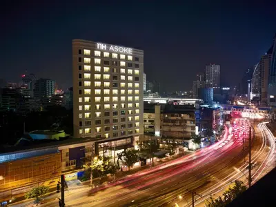 a building with a sign on the top of it at night at NH Bangkok Asoke in Bangkok
