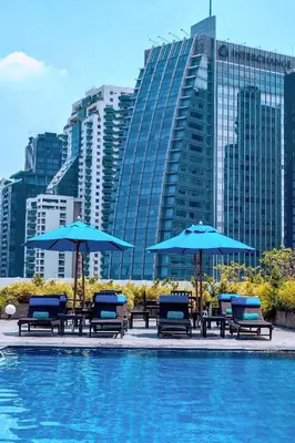 a group of chairs and umbrellas next to a pool at NH Bangkok Asoke in Bangkok