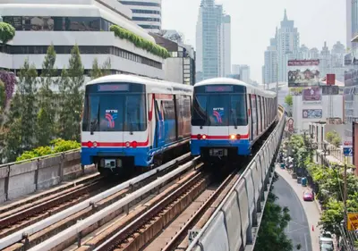 two trains on tracks in a city with buildings at NH Bangkok Asoke in Bangkok