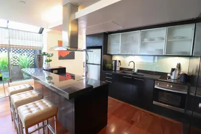 a kitchen with black cabinets and a sink and a counter at The Quarter Saladaeng by UHG in Bangkok
