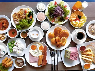 a wooden table with plates of food on it at The Quarter Saladaeng by UHG in Bangkok