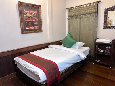 a small bedroom with a bed with a green pillow at The Siam Heritage Hotel in Bangkok