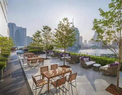 a patio with tables and chairs and a view of a city at Millennium Hilton Bangkok in Bangkok