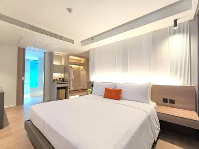 a bedroom with a large white bed with an orange pillow at Citrus Sukhumvit 13 Nana Bangkok by Compass Hospitality - Newly Renovated in Bangkok