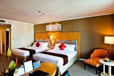 a hotel room with two beds and a desk at Royal Princess Larn Luang - SHA Extra Plus in Bangkok