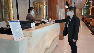 a man in a suit wearing a mask at a counter at Royal Princess Larn Luang - SHA Extra Plus in Bangkok