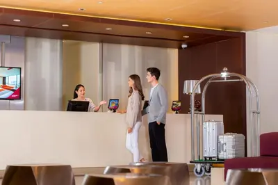 a man and a woman standing at a counter at Pathumwan Princess Hotel in Bangkok