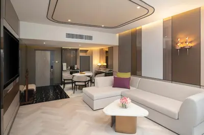 a living room with a white couch and a table at Pathumwan Princess Hotel in Bangkok