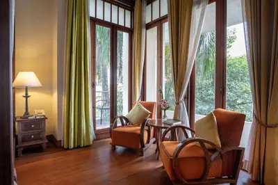 a living room with chairs and a table and windows at Ariyasom Villa in Bangkok