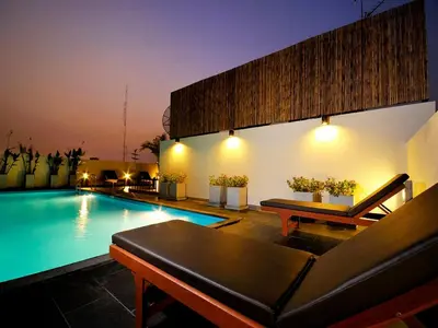 a swimming pool with a couch and a table at Sleep Withinn in Bangkok
