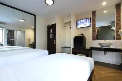 a bedroom with two beds and a sink and a television at Sleep Withinn in Bangkok