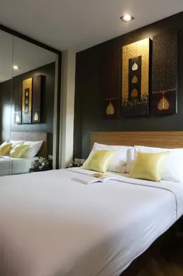 a large white bed in a room with a mirror at Sleep Withinn in Bangkok