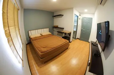 a small bedroom with a bed and a flat screen tv at Inn Trog And Inn Soi in Bangkok
