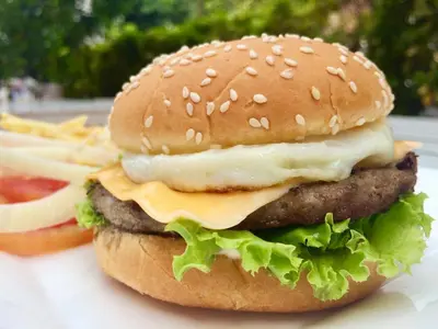 a hamburger with cheese and lettuce next to some fries at Vabua Asotel Bangkok in Bangkok