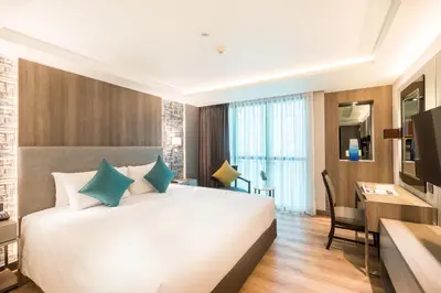 a bedroom with a large white bed and a desk at Citrus Suites Sukhumvit 6 by Compass Hospitality in Bangkok