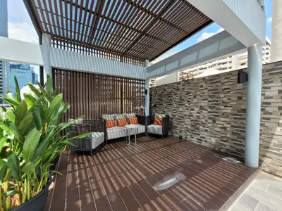 a patio with a wooden deck with chairs and a brick wall at Citrus Suites Sukhumvit 6 by Compass Hospitality in Bangkok