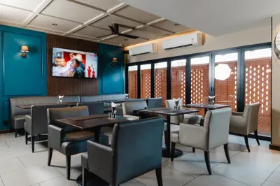 a dining room with tables and chairs and a tv at The Dawin Hotel in Bangkok