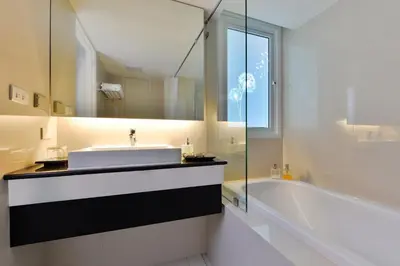 a bathroom with a sink and a tub and a mirror at Le D'Tel Bangkok in Bangkok