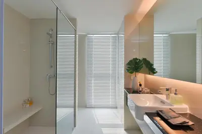 a white bathroom with a sink and a shower at Le D'Tel Bangkok in Bangkok