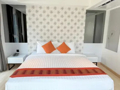 a bedroom with a white bed with orange pillows at Le D'Tel Bangkok in Bangkok