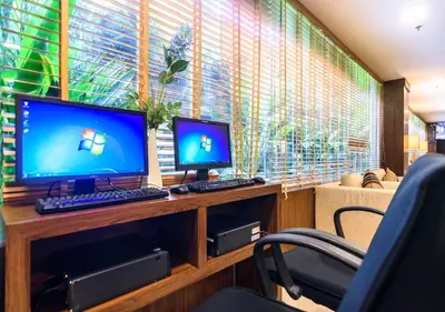 two computer monitors sitting on a desk with a chair at Lohas Residences Sukhumvit 2 in Bangkok