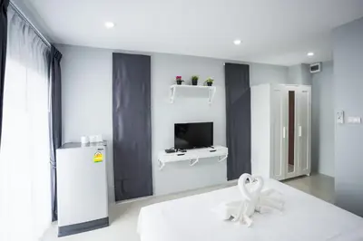 a white room with a television and a white flower on a bed at Twentynine KV Apartel in Nonthaburi
