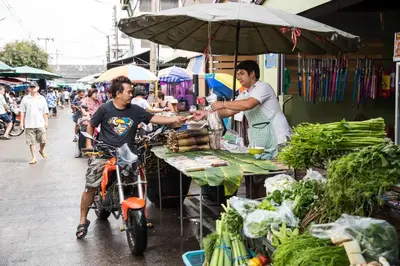 a man on a bike buying food at an outdoor market at Twentynine KV Apartel in Nonthaburi