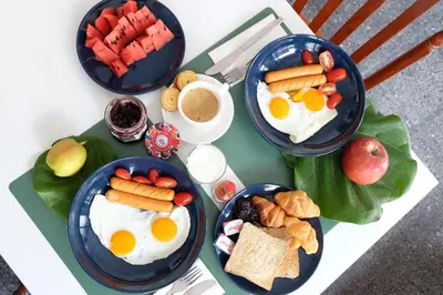 a table with three plates of breakfast food on it at Haus Sathorn 21 Bed and Breakfast in Bangkok