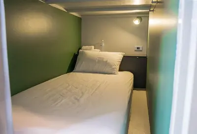 a small bedroom with a bed in a green wall at Yaks House Hostel in Bangkok