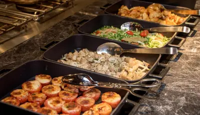 three trays of food on a counter with spoons at Bangkok Marriott Hotel The Surawongse in Bangkok