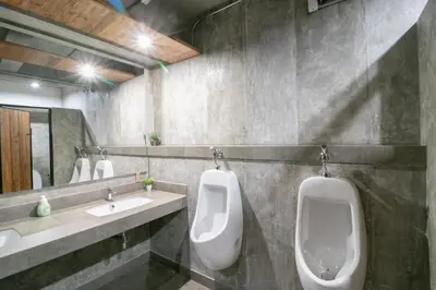 two urinals in a bathroom with two sinks and two toilets at Zleepmotion Bangkok in Bangkok