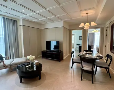 a living room with a table and a couch and a tv at Rongratana Executive Residence Bangkok in Bangkok