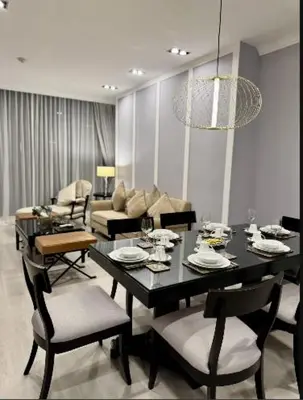 a dining room with a table and chairs and a couch at Rongratana Executive Residence Bangkok in Bangkok