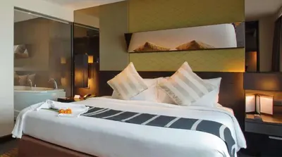 a hotel room with a large bed and a bath tub at Golden Tulip Mandison Suites in Bangkok