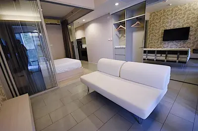 a living room with a white couch and a bed at BoonRumpa Accommodation in Bangkok