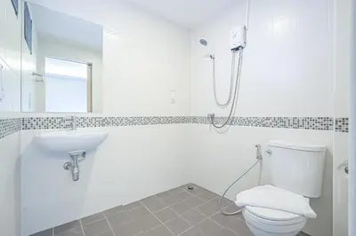 a white bathroom with a toilet and a sink at Sleep Hotel Bangkok in Bangkok