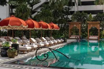 a swimming pool with chairs and umbrellas in a hotel at Anantara Siam Bangkok Hotel in Bangkok