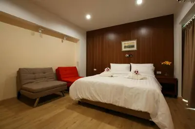 a bedroom with a large bed and a chair at Baanthanam Nont in Nonthaburi