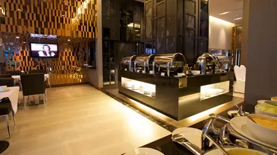 a restaurant with a counter with plates of food at M2 de Bangkok Hotel in Bangkok