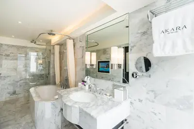 a white bathroom with a sink and a mirror at Akara Hotel in Bangkok